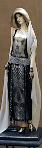 This may contain: a statue of a woman wearing a dress and hat with pearls on it's head