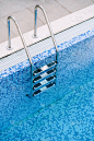 泳池楼梯的特写，以蓝色马赛克为背景。