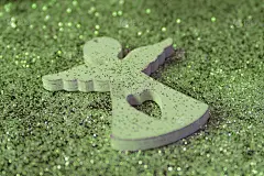 一个白色小天使的木制小雕像在闪亮的绿色背景上。圣诞假期的概念。