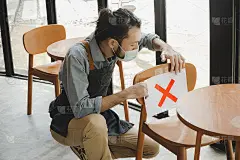 餐厅服务员戴上防护面罩，在座位上放置纸上的距离标志，以保护感染新冠病毒(covid-19)，这是新常