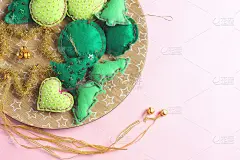 在盘子里放着手工制作的圣诞树和绿色小球。粉红色的背景。平铺，拷贝空间