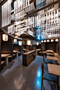 Industrial Interior Design - This Restaurant and bar goes for a warehouse chic style with metal, concrete, and wood. Inside the square dining room of this modern restaurant, lighted boards hang from the ceiling as a nod to the neon signs that light up the