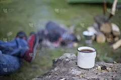 一个人在帐篷营地的火上煮咖啡。