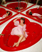 a woman laying in a red bathtub surrounded by mirrors