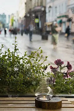 木桌上烛台上的蜡烛的特写，咖啡馆里温暖舒适。城市里的雨天
