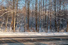 水平白雪覆盖的道路在冬季森林的日落。冬季景观与道路出版，海报，日历，帖子，屏保，壁纸，明信片，横幅，