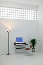 A white room with a computer and a plant