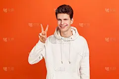 快乐积极的青少年在时尚的运动衫显示v标志对着镜头，眨眼和微笑，年轻人希望好运，和平