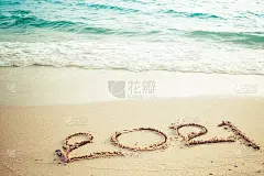 新年快乐2021概念，2021数字字母在海滩上，海浪和夕阳的金色光芒。