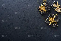 假日礼品盒或礼品带，金色的纸屑和金色的小玩意在黑色的背景上。神奇的圣诞贺卡。圣诞装饰。边界设计。模拟