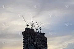 塔吊在日落的背景施工现场行动。用起重机建造高层建筑。新住宅的摩天大楼。高层住宅改造工程，政府项目