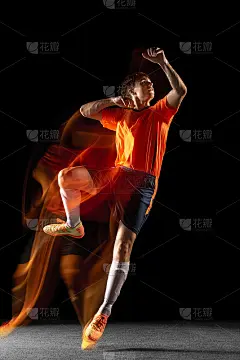 年轻的白人男子足球或足球运动员踢球为目标在混合光在黑暗的背景。健康生活理念，职业运动，爱好。