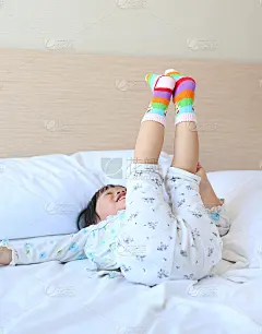 可爱的亚洲小女孩试图把袜子放在床上。