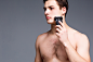 unshaven-man-with-naked-torso-looking-forward-using-trimmer