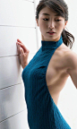 This may contain: a woman in a blue dress leaning against a wall