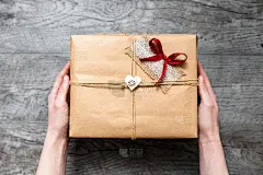 女人手里拿着包装好的礼物，情人节，浪漫的照片。浪漫的灰色木质背景，配爱心礼品，适合做广告