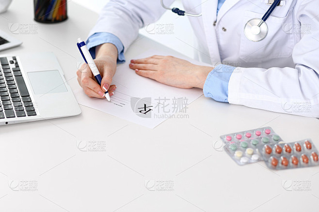 女医生填写处方表格，而坐在桌子上的医院特...