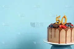 巧克力生日蛋糕，浆果，饼干和50号金色蜡烛蓝色背景墙，复制空间