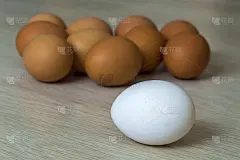 厨房餐桌上的灯光背景上放着白色的大鸡蛋和一组黄色的鸡蛋。健康有机食品，美味佳肴，胆固醇和饮食理念。