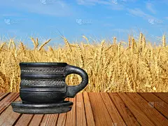 老黑茶杯在木质表面上衬着金黄色的小麦。