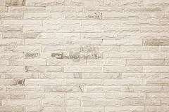 宽奶油色砖墙纹理的空背景。米色旧棕色砖墙混凝土或石材纹理，壁纸石灰石抽象地板/网格不均匀的内部岩石。