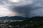 Mountains and city shrouded by storm clouds at sunset.