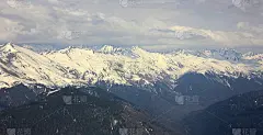 从山顶俯瞰。蓝雾中的山谷和雪山。峡谷和多云的天空。索契,俄罗斯。