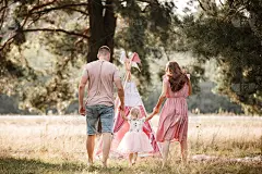 幸福家庭的画像。妈妈，爸爸和女儿在公园里散步。年轻的家庭花时间在一起度假，户外。暑假的概念。母亲的，