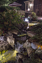 Backyard waterfall lit at night with LED pond and landscape lighting.