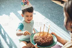 可爱的孩子戴着派对帽，妈妈给他生日蛋糕