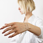 Cropped shot of young blonde woman with straight hair wearing silver chain with a pendant isolated on a gray background Chain necklace on female hand