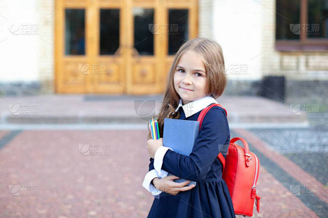 小学的女学生正在上学的路上。开始上课。小女孩就在学校附近。带着一本书、铅笔和书包的女学生。回学校去教