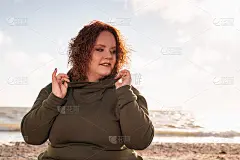 一个胖女人的肖像正坐在海边微笑着。背景是天空和海洋。成功的概念和心理学