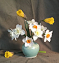This may contain: a blue vase filled with white and yellow flowers on top of a gray table cloth