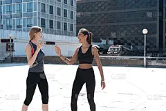 两个快乐的女人穿着健身服在城市里跑步时击掌