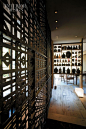 The custom iron screen\'s latticework combines traditional Japanese patterns. Earthenware jars and reclaimed pine shelving compose the other screen.