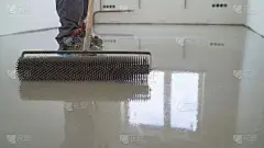 师傅用滚针器。填充层。一个承包商油漆工将油漆车库地板，以加快你的房子出售。地板找平的填充、修补和整理