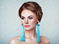 美丽的女人带着大耳环和宝石蓝色.完美的化妆和优雅的发型。蓝色化装箭