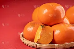 新鲜漂亮的甜柿子切片，孤立在红表背景和竹筛，中国农历新年的设计理念。