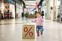 聪明的自然友好的黑色星期五销售概念。小可爱的小女孩跑到带有%标志的环保纸袋里购物。软焦点，模糊背景