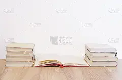 成堆的书放在木桌和白色的墙壁上
