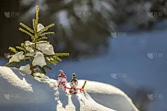 两个有趣的小玩具娃娃雪人在编织的帽子和围巾在深雪户外附近的松树树枝。新年快乐，并附上圣诞贺卡。