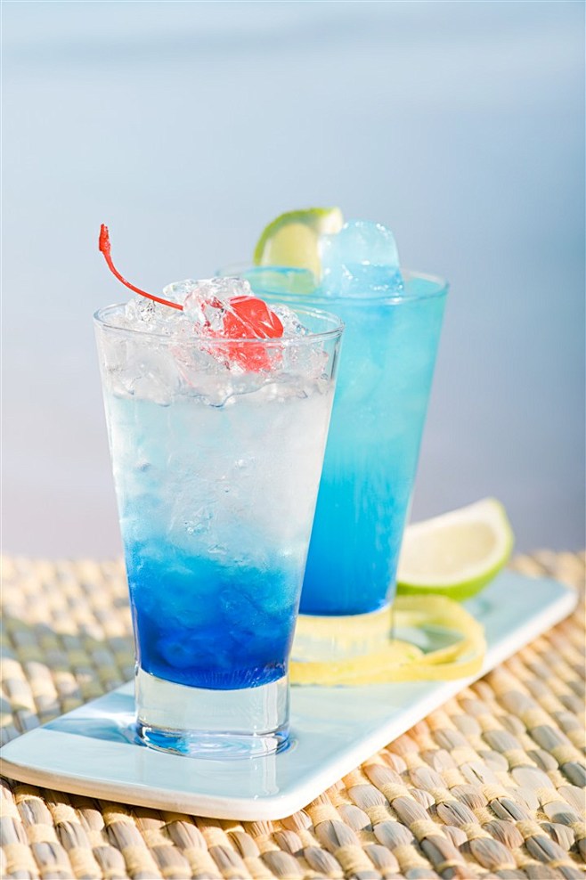 阳光海边竹垫上的蓝色冰镇水果柠檬鸡尾酒果...