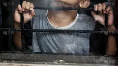 用格子窗。一只手抓住了棚架。那男孩紧抓着棚架。