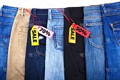 商店出售的衣服，打折，牛仔裤不同颜色的蓝色，绿色，黑色在白色的背景孤立近距离