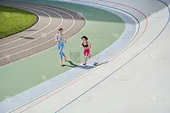 一个矮个子女人和她最好的朋友在体育场跑步