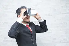 戴着虚拟现实眼镜的商人。戴着VR头盔的年轻人正在看交互式屏幕。在设备上玩手机游戏应用。