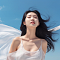 A Korean beauty with very white and delicate skin, enjoying the sun outdoors with a natural expression on her face, and long fine black hair cascading down. She is featured in a whitening skincare product advertisement poster with a blue sky and white clo