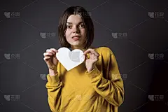 一个年轻的女孩拿着一张白纸心-一张明信片为了写爱。