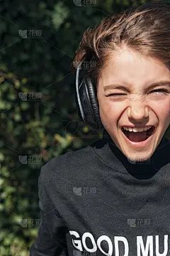 小女孩穿着黑色的运动衫，戴着耳机听音乐，面带微笑